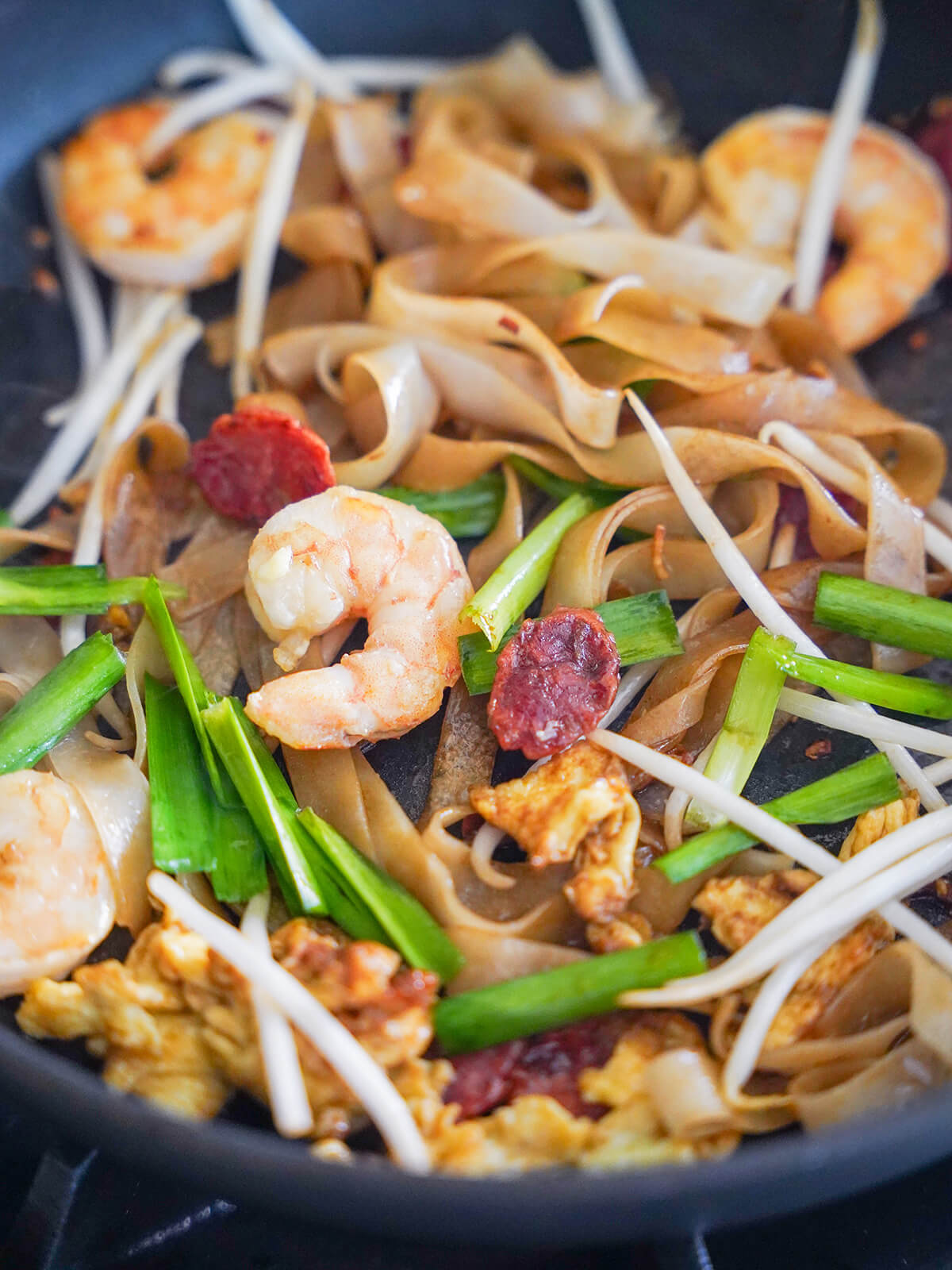cooking noodles, bean sprouts and shrimp in skillet.
