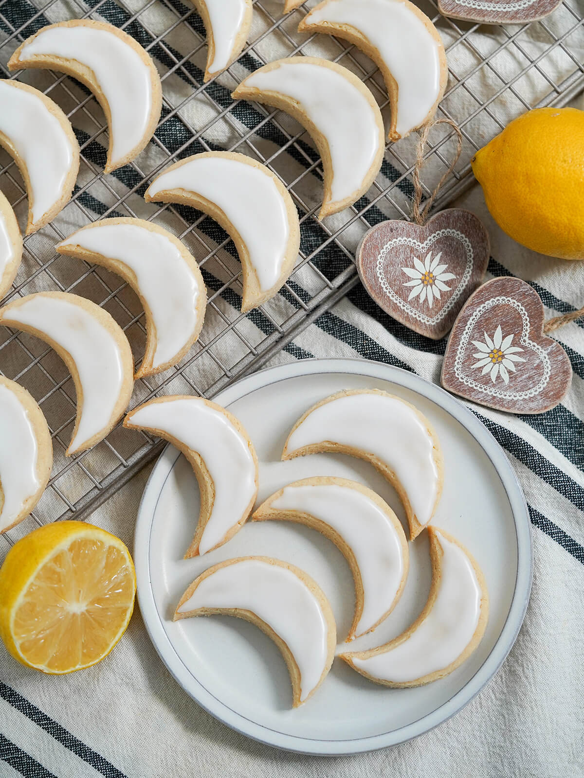 lemon almond cookies Zedernbrot from overhead overhead view of plate of lemon almond cookies zedernbrot with more on cooling rack to side and lemons to wither side.