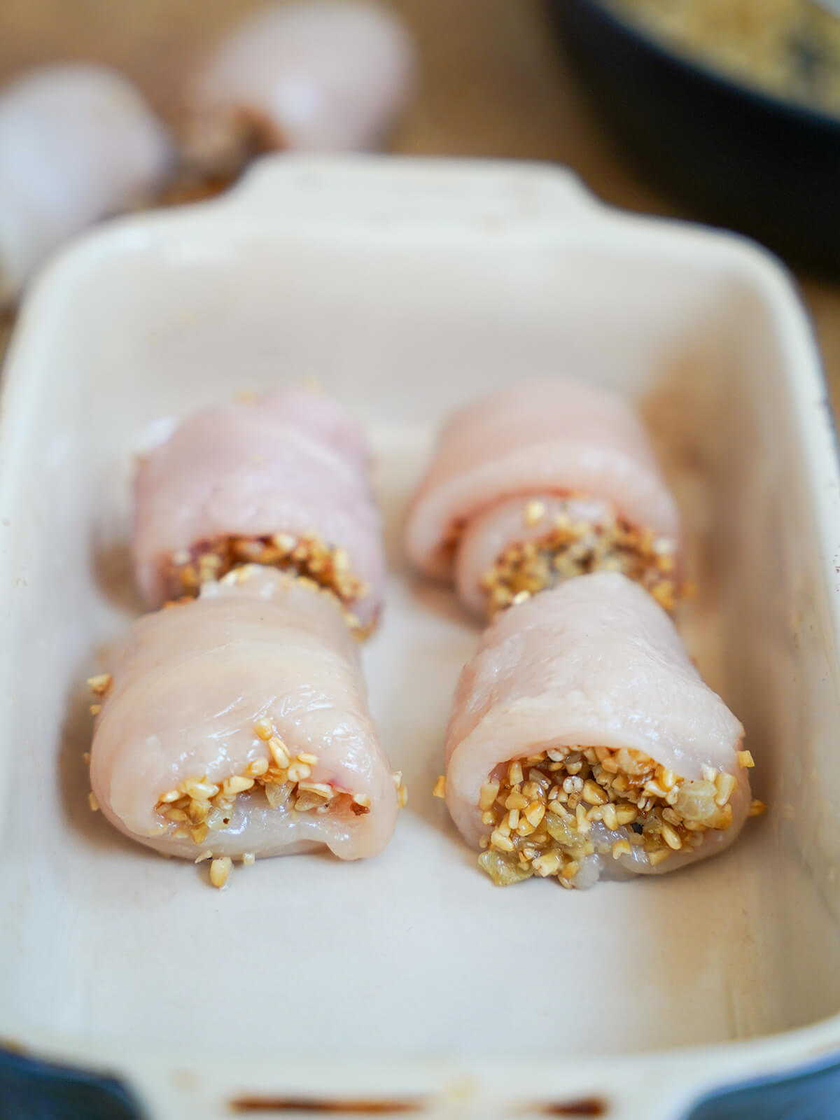 pieces of chicken with oatmeal filling in baking dish before cooking in oven.