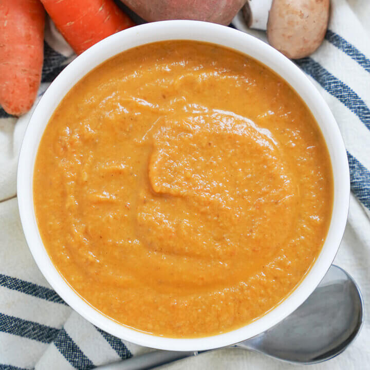 close view of bowl of mushroom carrot and sweet potato soup with spoon under bowl.