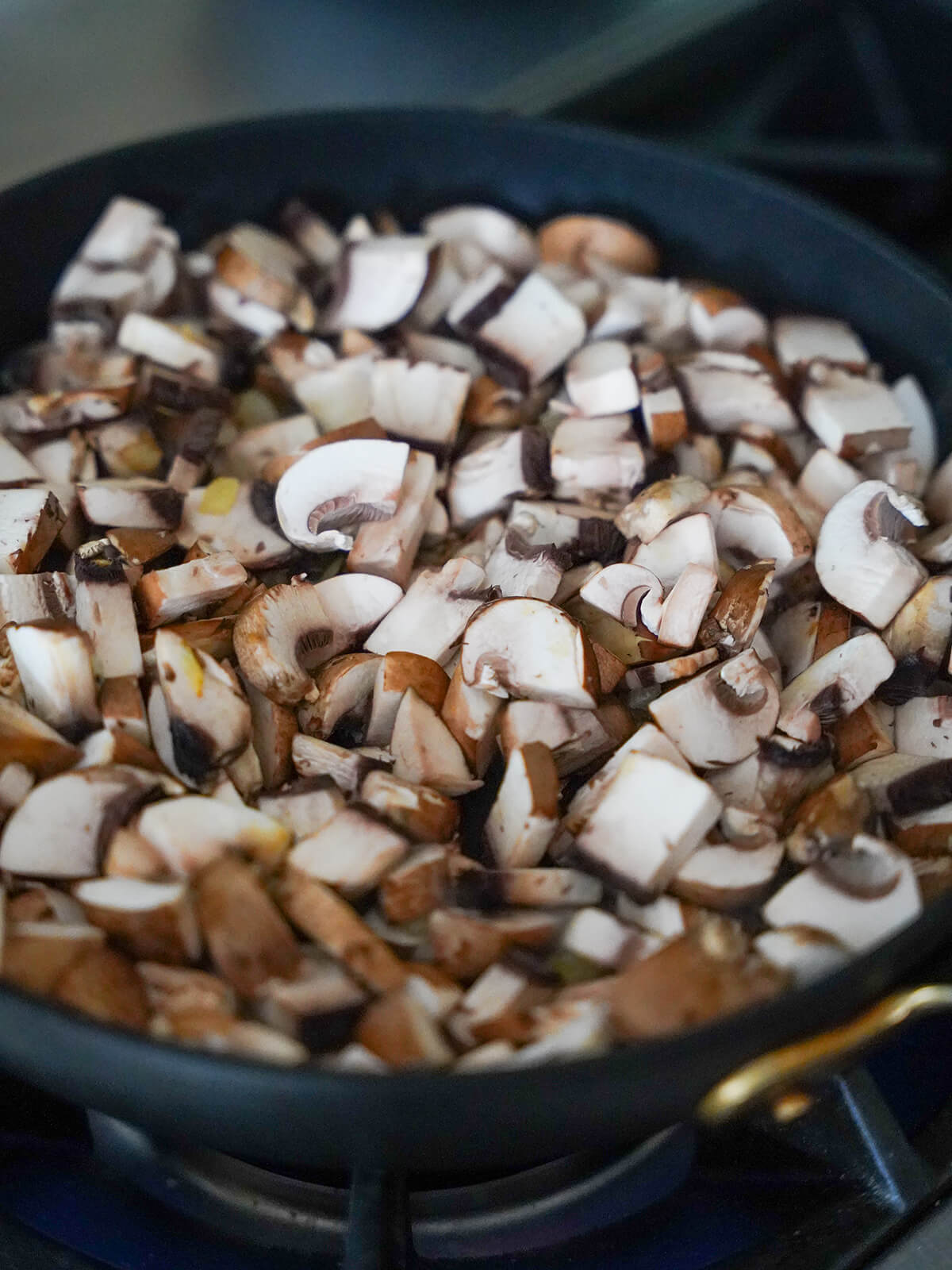 adding mushrooms to skillet for mushroom stroganoff chopped mushrooms added to skillet before they cook down.