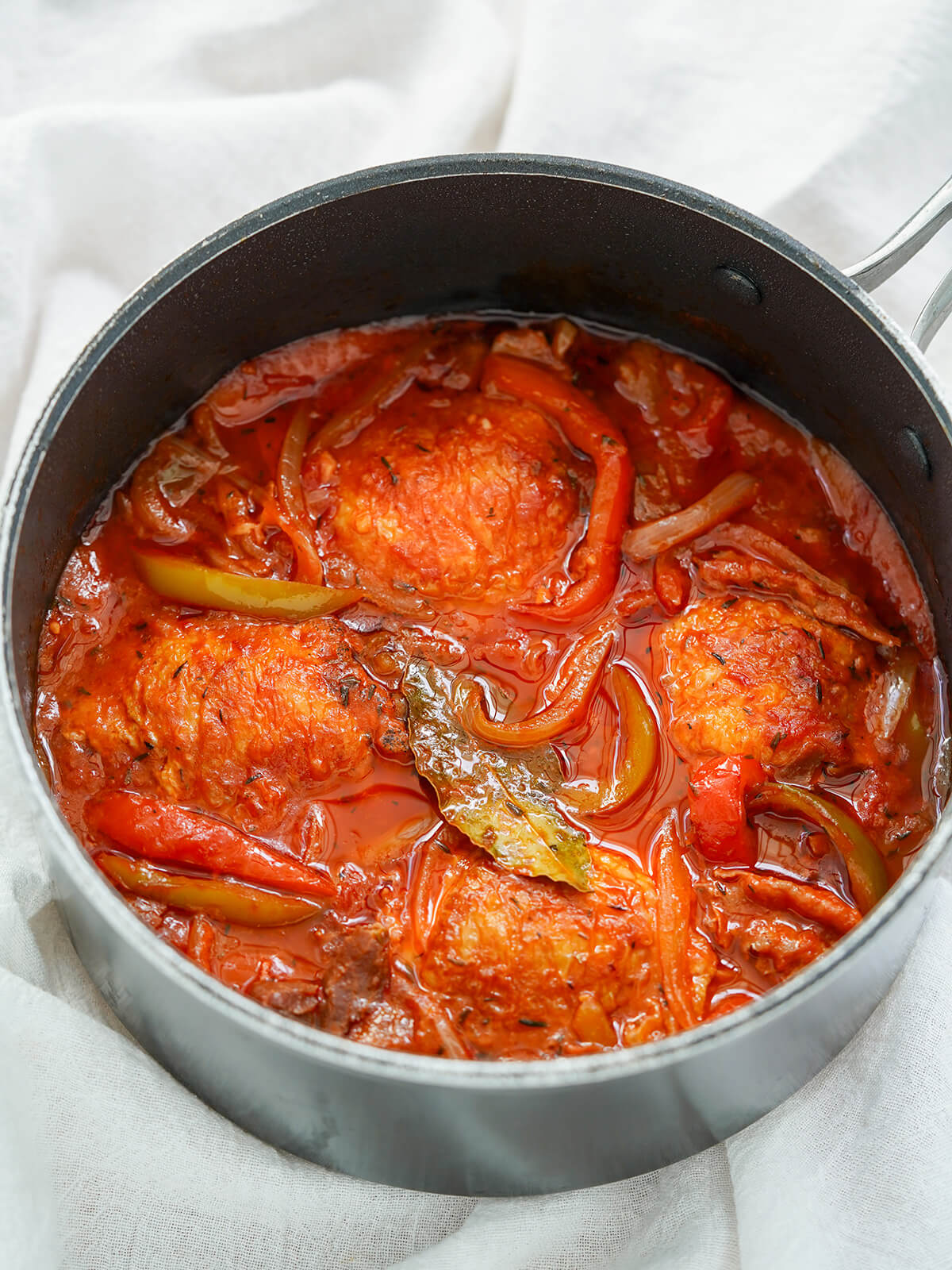 pot of Basque chicken with peppers, bay leaf showing on top.