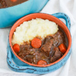 close view of bowl of Guinness beef stew with mashed potatoes at side of bowl.