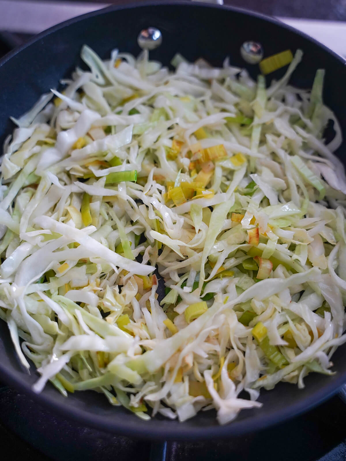 cooking cabbage for colcannon cooking cabbage and leek in skillet.