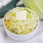 bowl of colcannon, mashed potatoes with cabbage, with pat of butter on top.