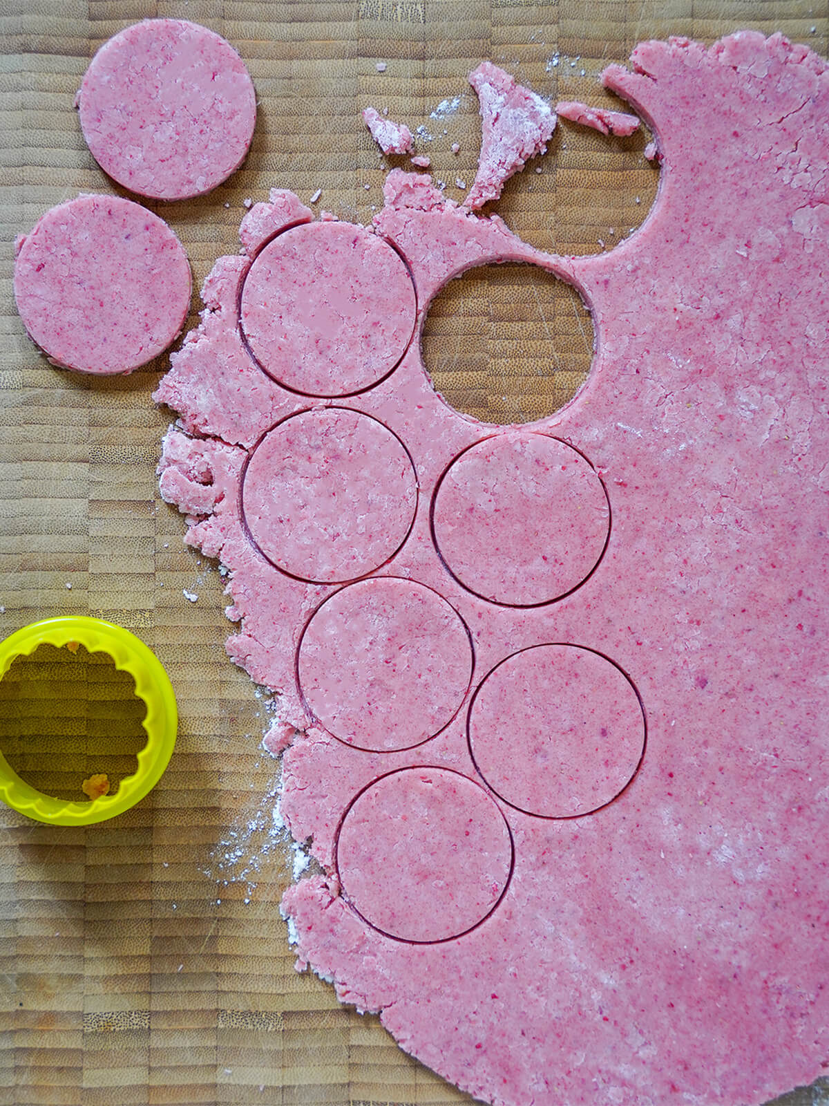 cutting out strawberry shortbread cookies cutting cookie circles from rolled out dough.