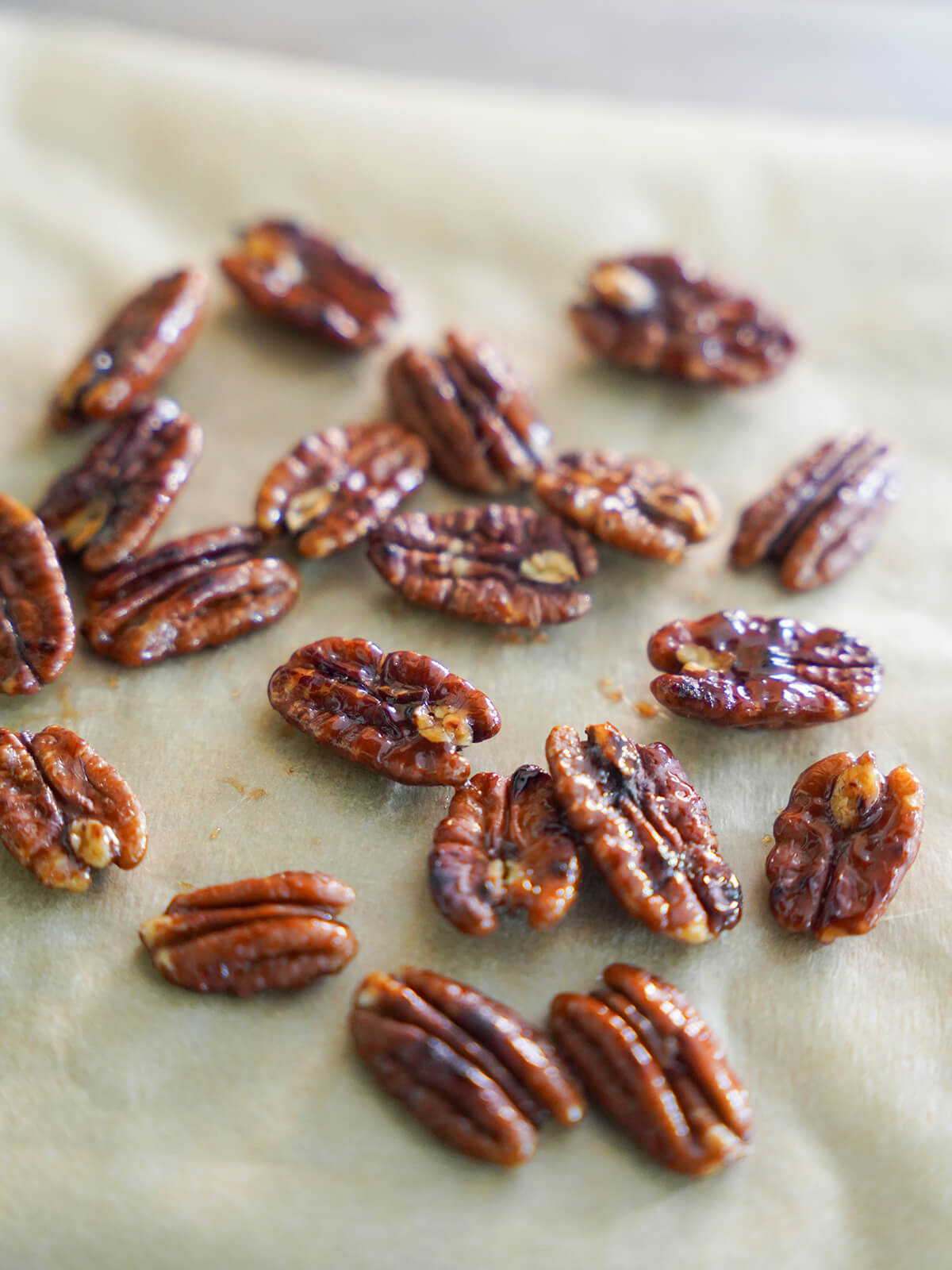 pecans on parchment, shiny from maple glaze.