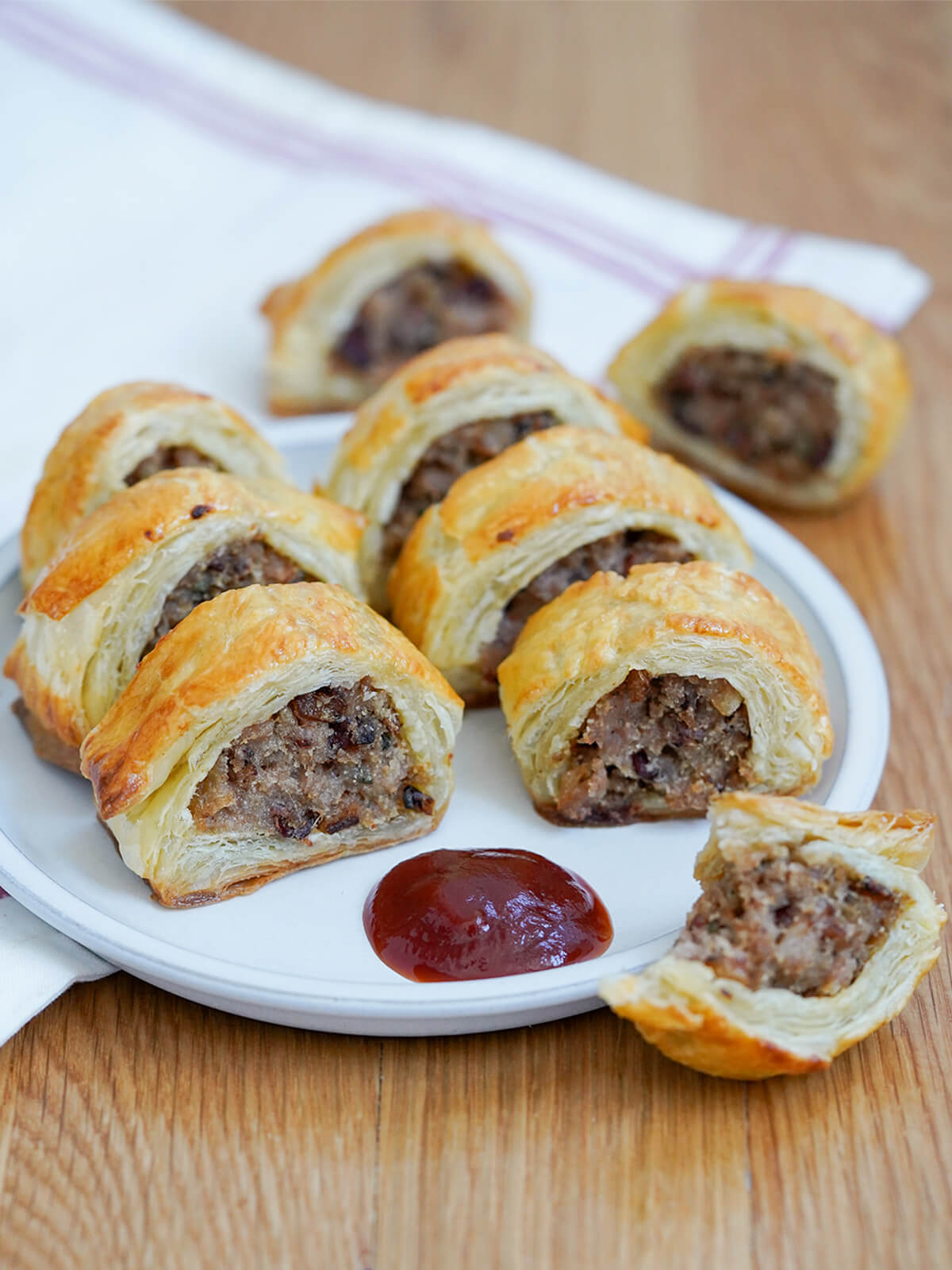 sausage rolls on a plate with some ketchup at front.