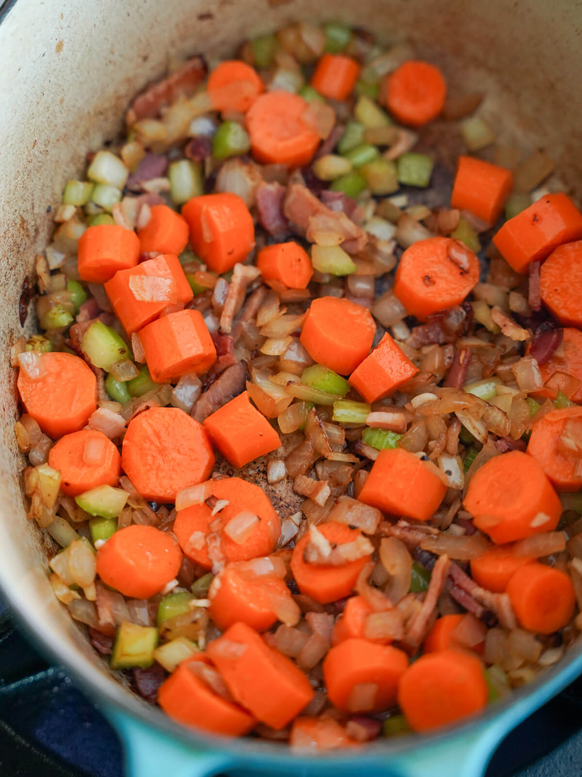 bacon, carrots, onion and celery softening in pot.
