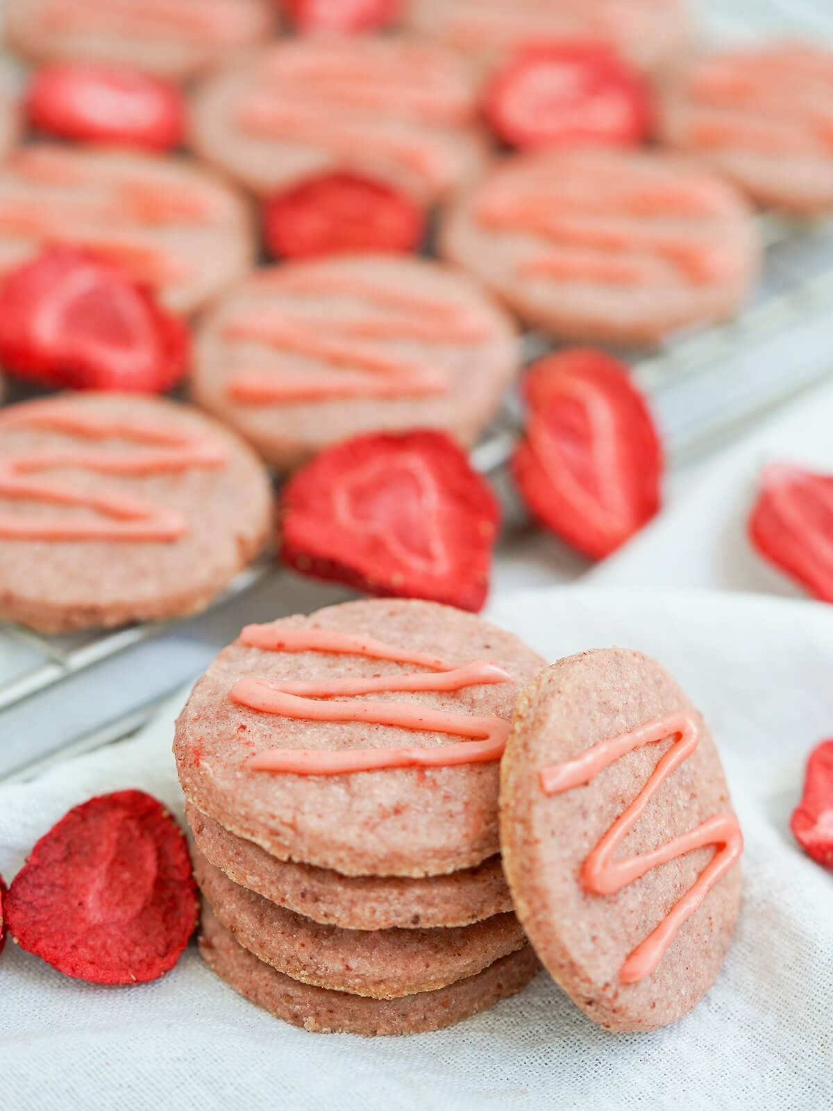 stacked strawberry shortbread cookies with one resting to side, more blurred in background.