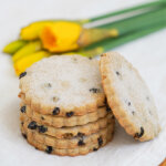 stack of Easter biscuits with one resting on side and daffodils blurred in background.