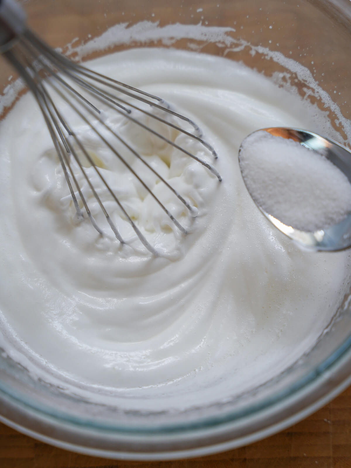 adding sugar to beaten egg white.