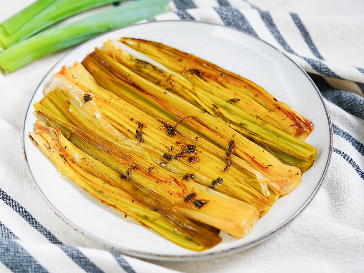 side view of plate of braised leeks topped with remaining butter and thyme.