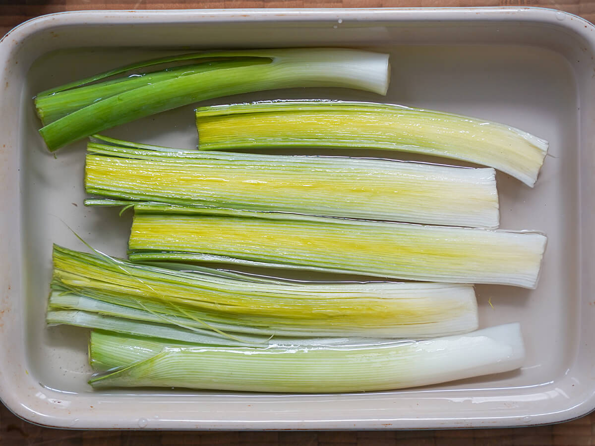 halved leeks in dish with water.