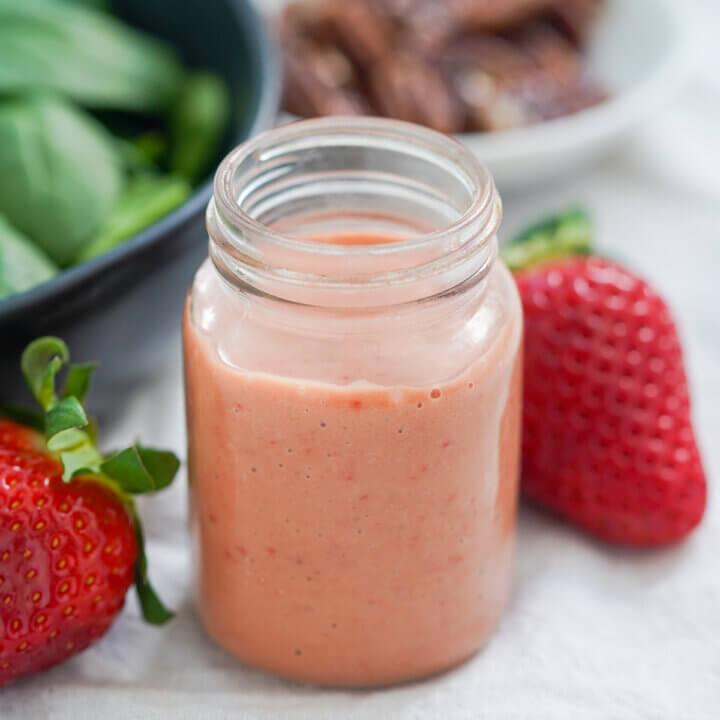 jar of strawberry balsamic vinaigrette with part view of strawberries either side.