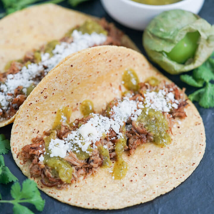 close view of taco topped with pork carnitas and salsa verde.
