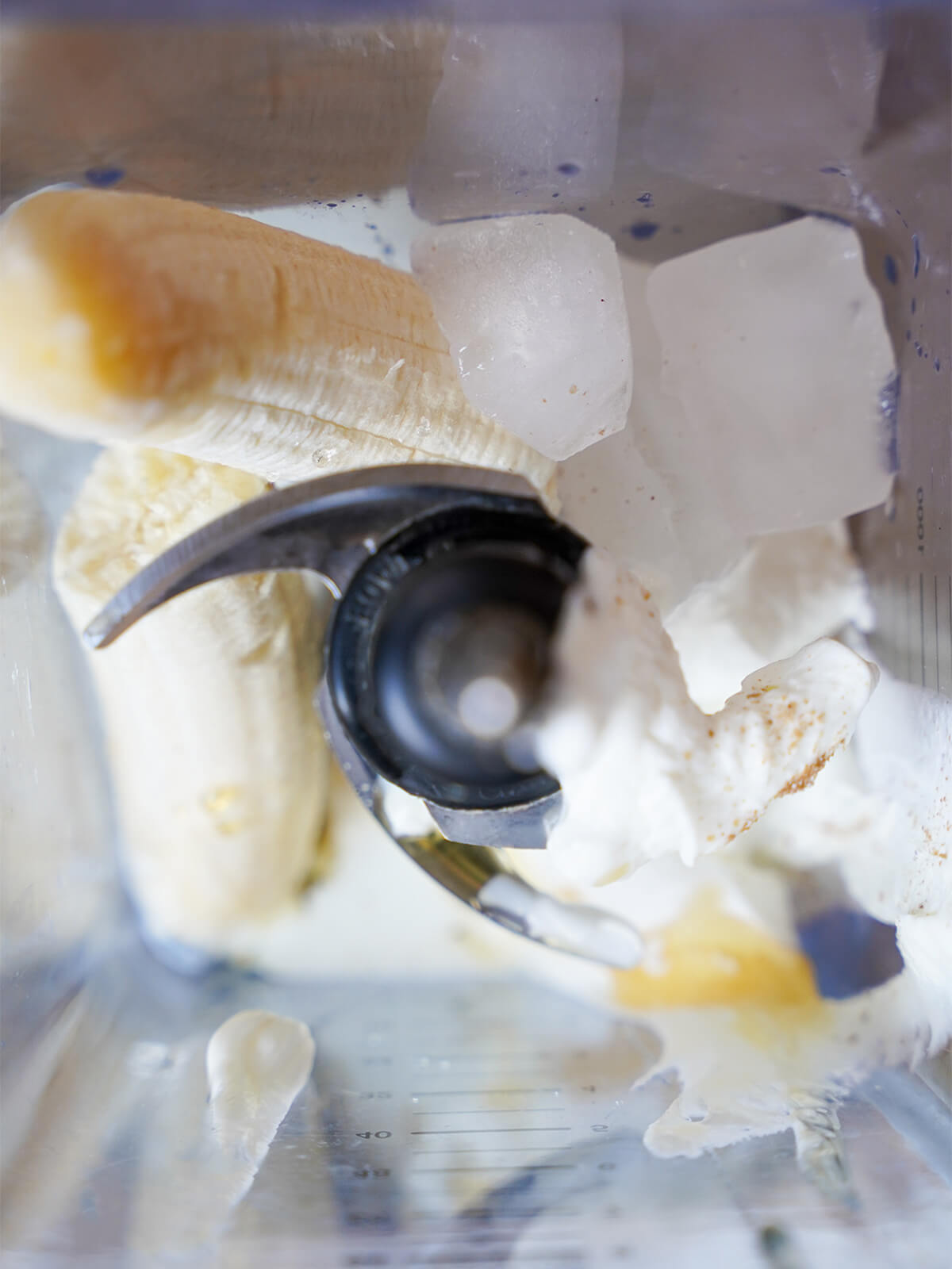 banana, ice, yogurt with small flecks of cardamom on top and honey drizzled down side in blender.