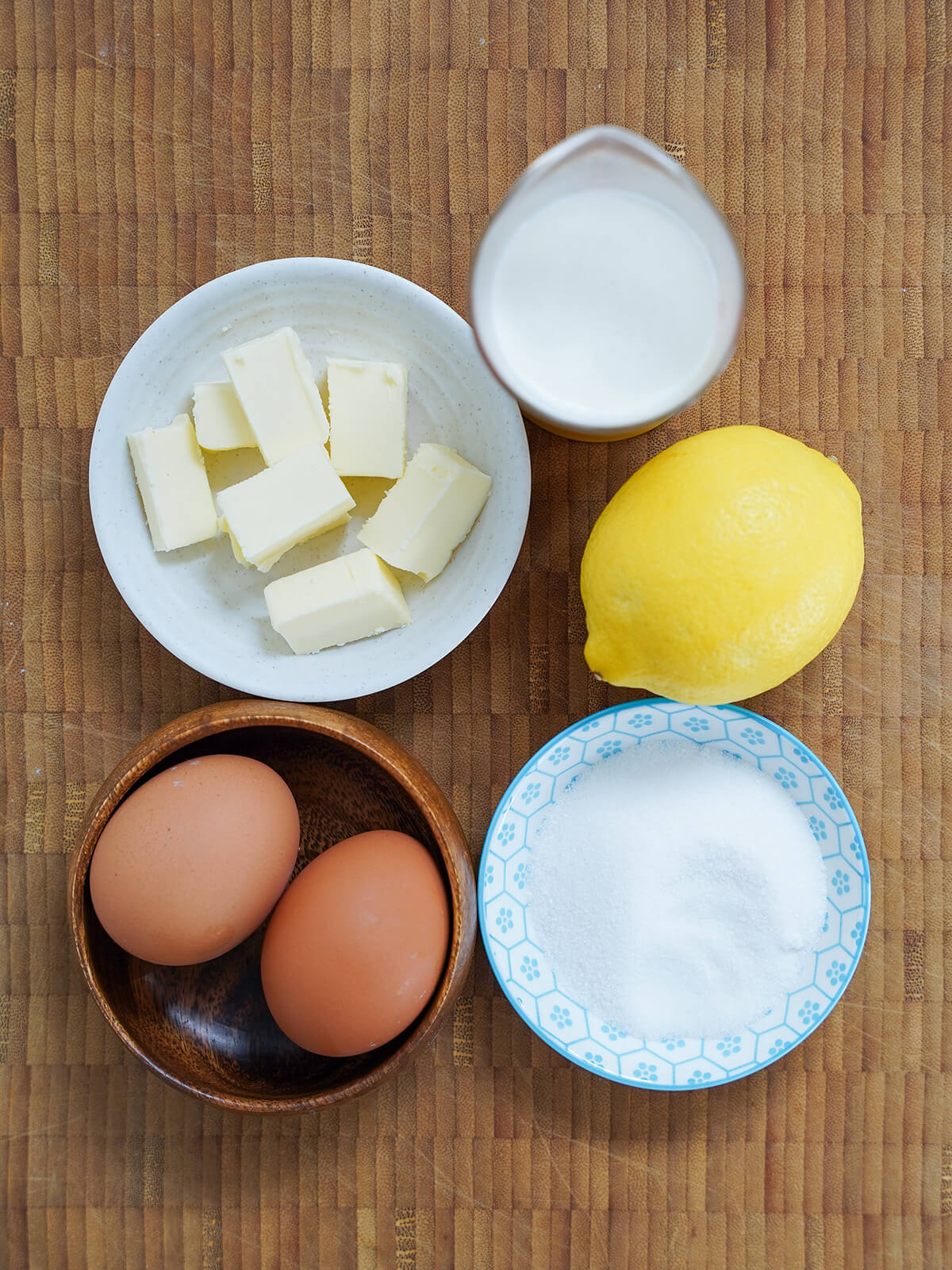dish with chunks of butter, measure of cream, lemon, eggs and dish with sugar.