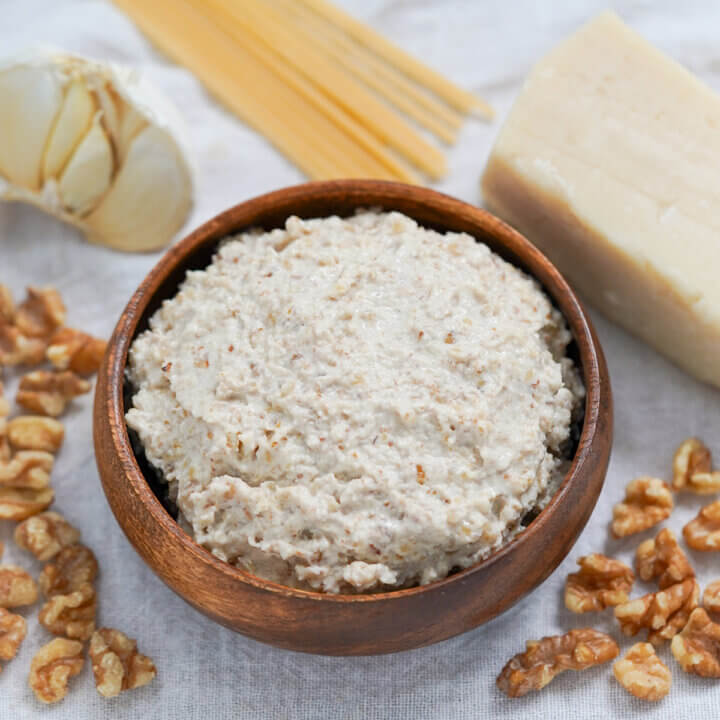 wooden dish with walnut sauce, salsa di noci with ingredients around it.