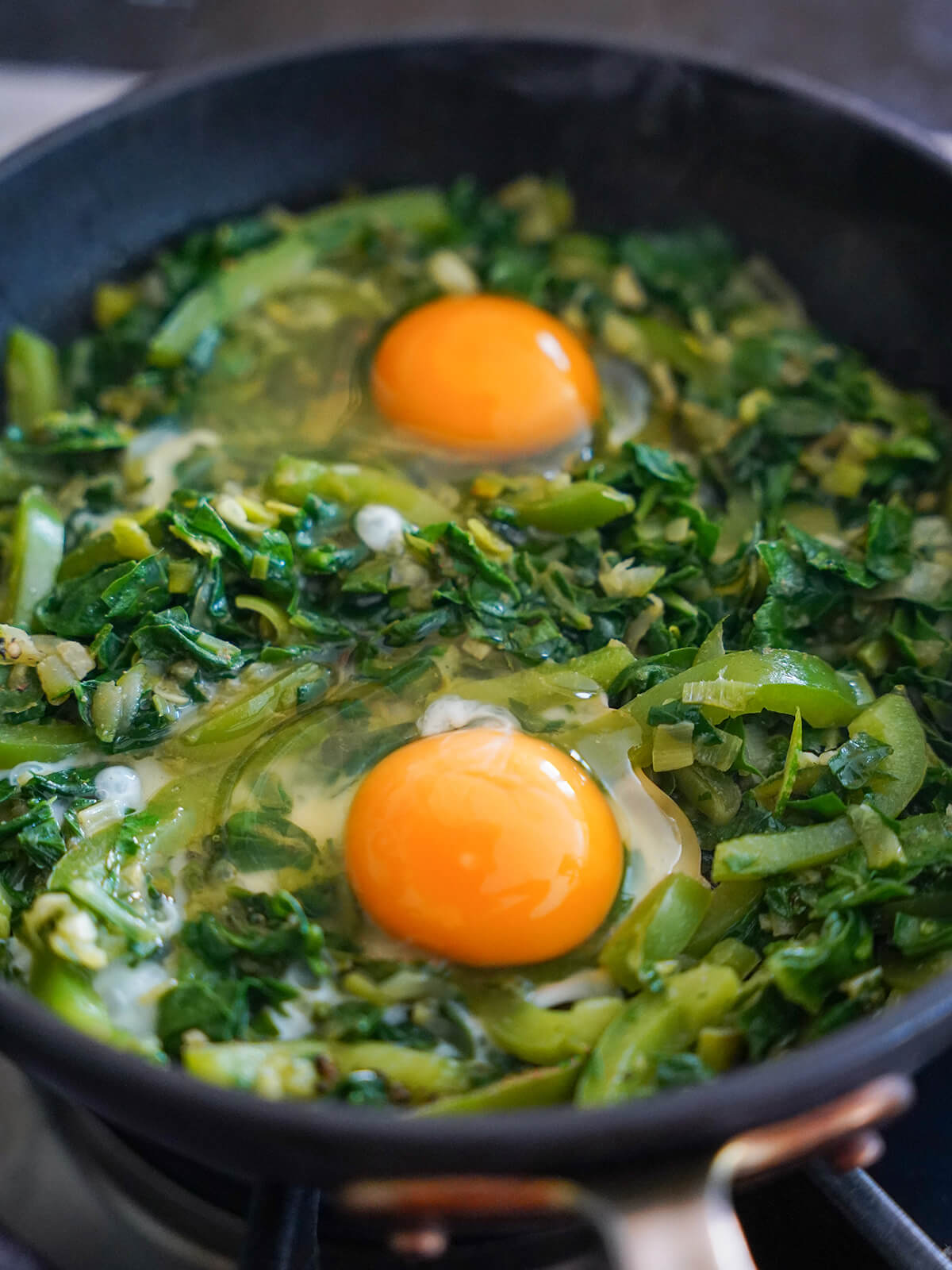 adding eggs into vegetable base in skillet.