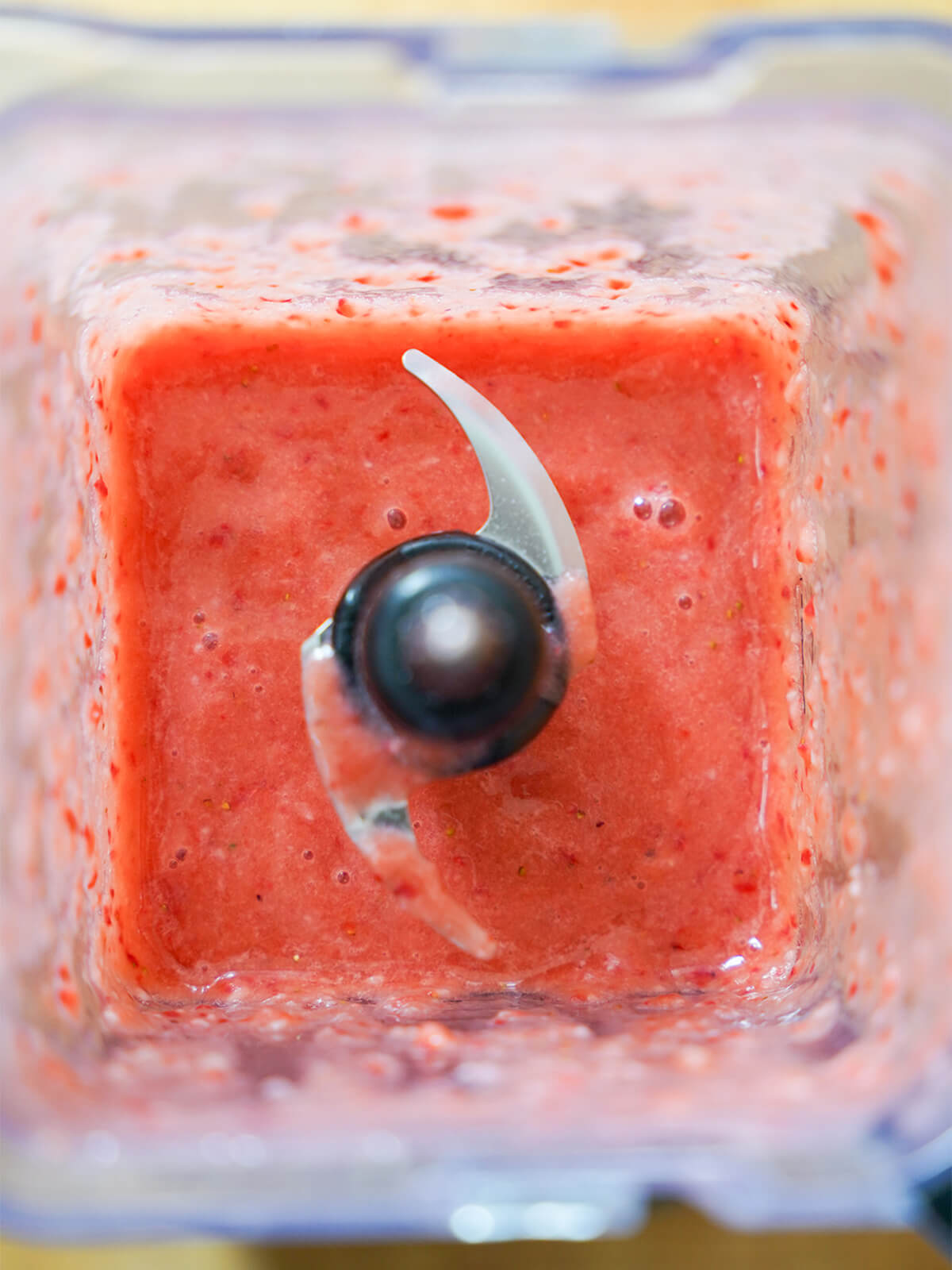 blender jug with pink blended fruit mixture in it.