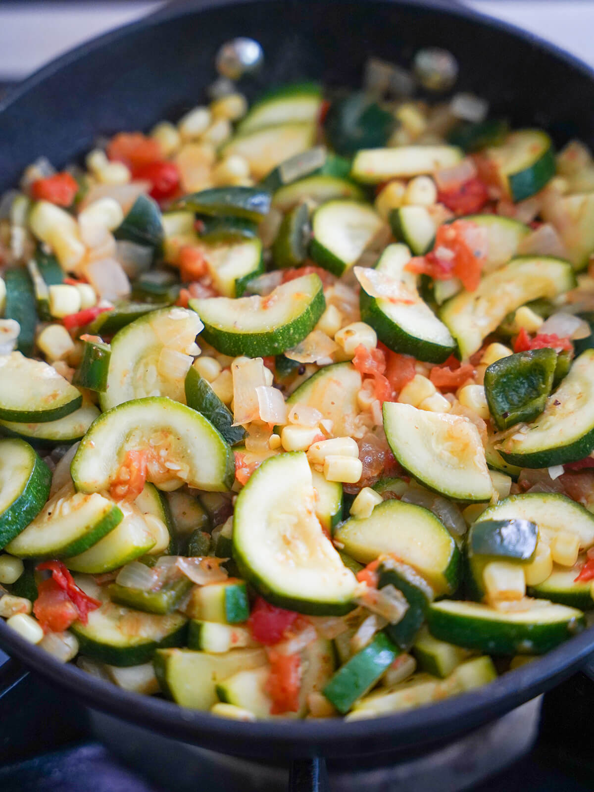 making calabacitas cooking calabacitas Mexican zucchini in skillet.