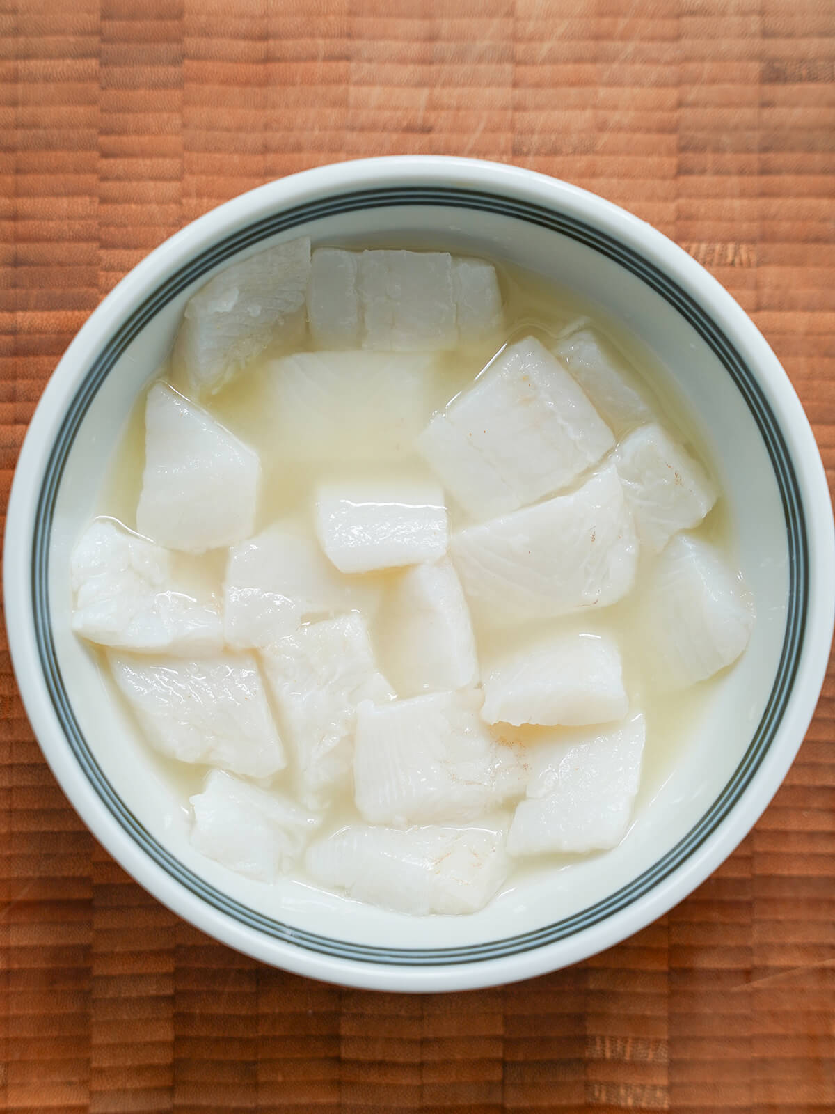 slices of fish in a bowl covered with citrus juice.