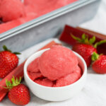 bowl of strawberry rhubarb sorbet with fruit either side.
