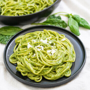 plate of tallarines verdes, often called Peruvian pesto, with basil sprig behind.