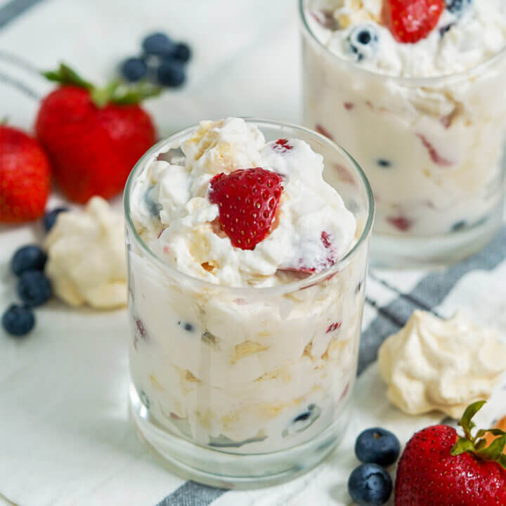 class of Eton mess with part view of a second glass behind and fruit around glasses.
