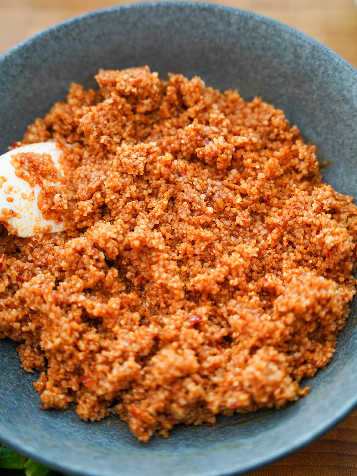 bulgur wheat with dressing mixed through for kisir bowl of bulgur wheat coated with tomato, lemon, oil and pomegranate dressing to become a red color.