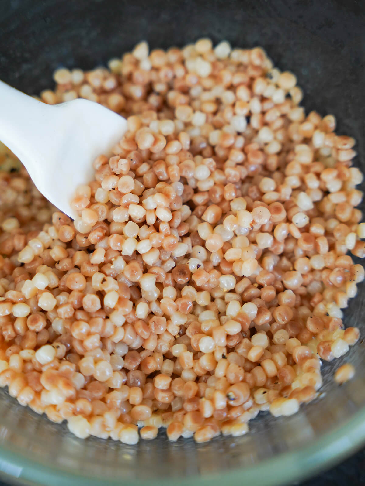adding dressing to pearl couscous for fruit couscous salad adding dressing to cooked pearl couscous