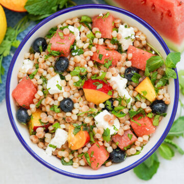overhead view of bowl of fruit couscous salad with herbs and feta.