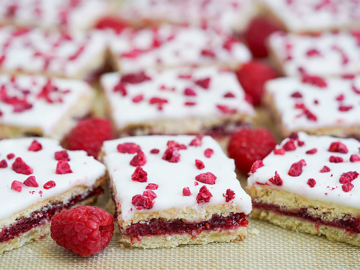 side view of hindbaersnitter Danish raspberry bars, with raspberries between the bars.