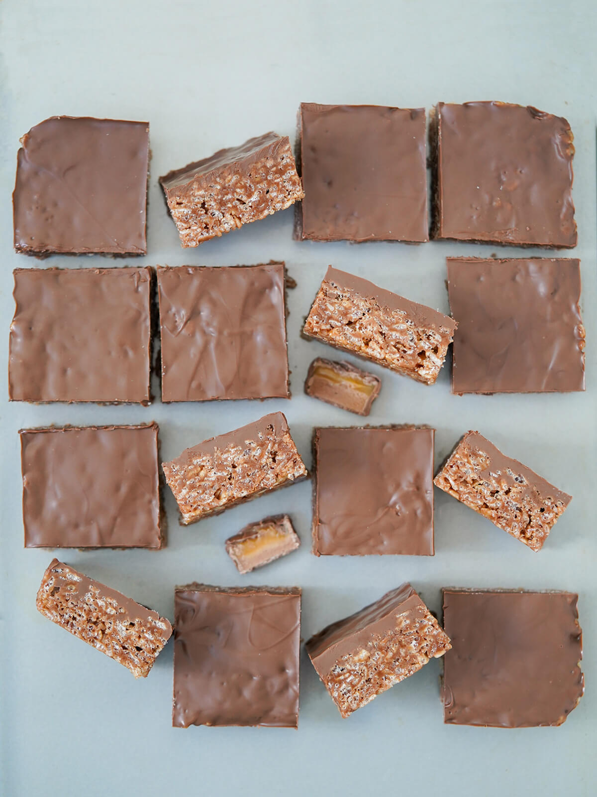 overhead view of pieces of mars bar slice on a baking sheet with some turned on side to show layers.