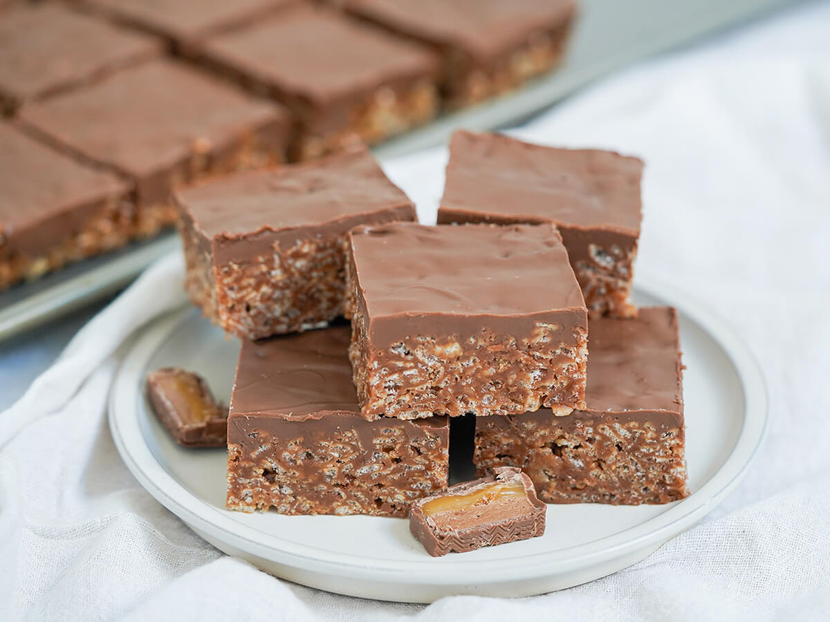 mars bar slice pieces on plate plate of mars bar slice pieces stacked in two layers with more blurred behind.