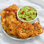 plate of patacones tostones with small bowl of guacamole at back of plate.