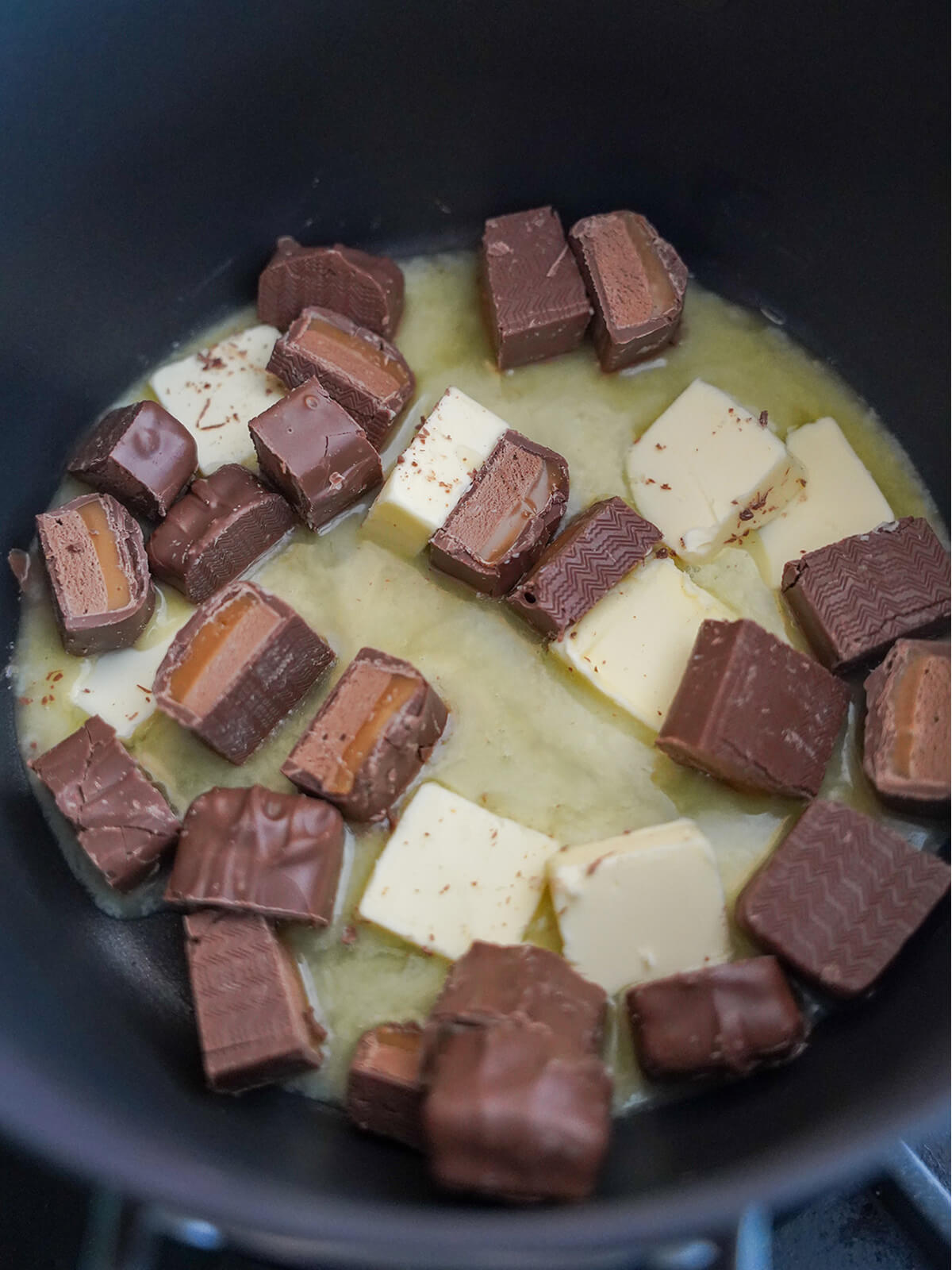 butter and mars bars melting together in pot chunks of butter and mars bar/milky way starting to melt in pot.