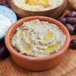 small dish of baba ghanoush, eggplant dip, with part view of other bowls of dips to side and behind.