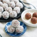 small plate of chocolate oat balls chokladbollar with more behind in background, some finished some still to roll in coconut.