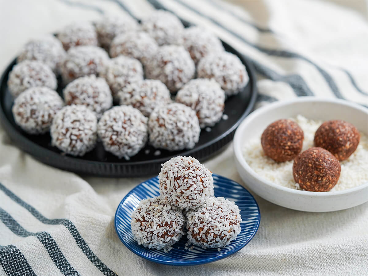 small plate of chocolate oat balls chokladbollar with larger plate of them behind.