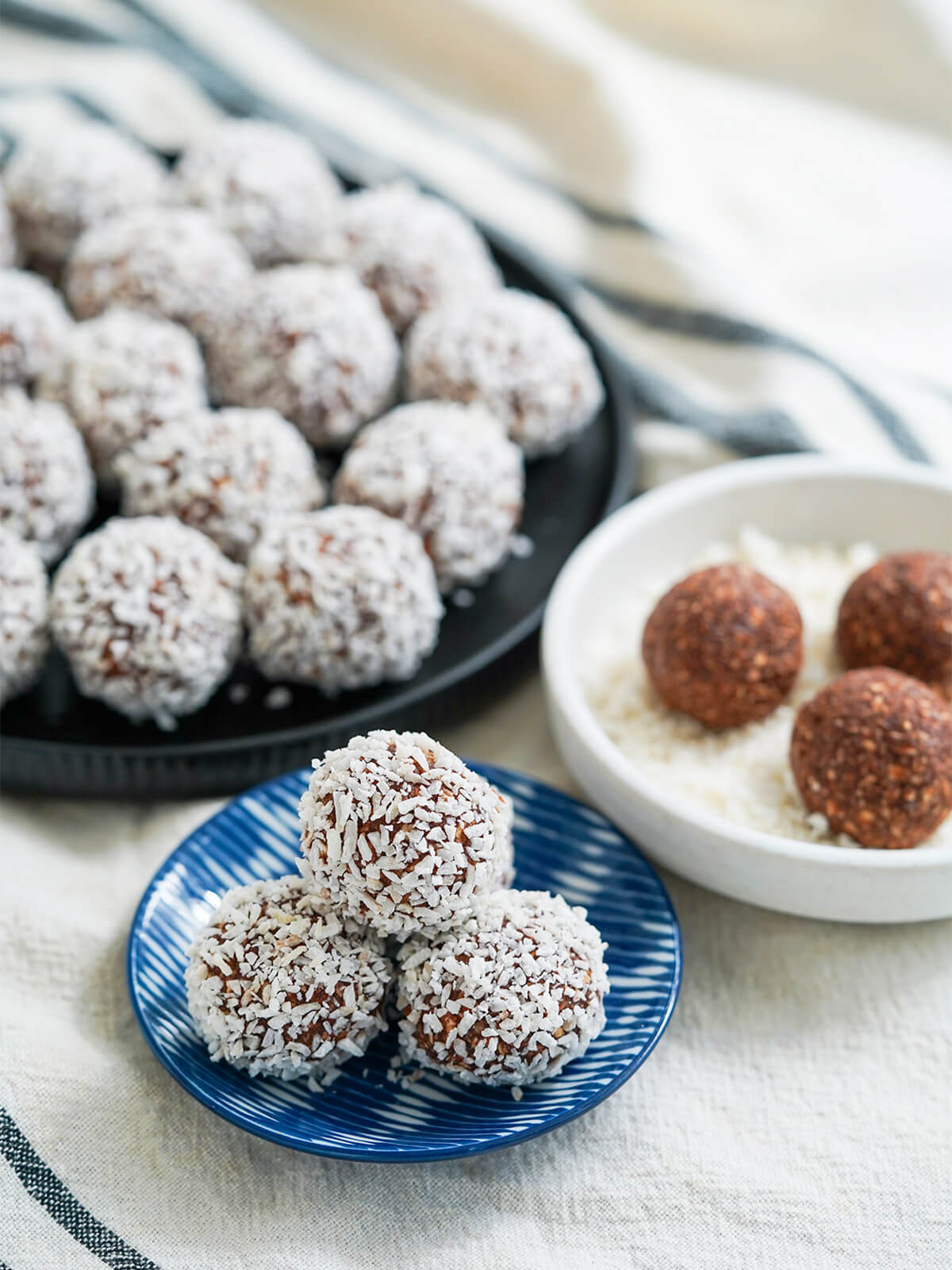 small dish of chocolate oat balls chokladbollar with larger dish in background and some un-coated in coconut to side.