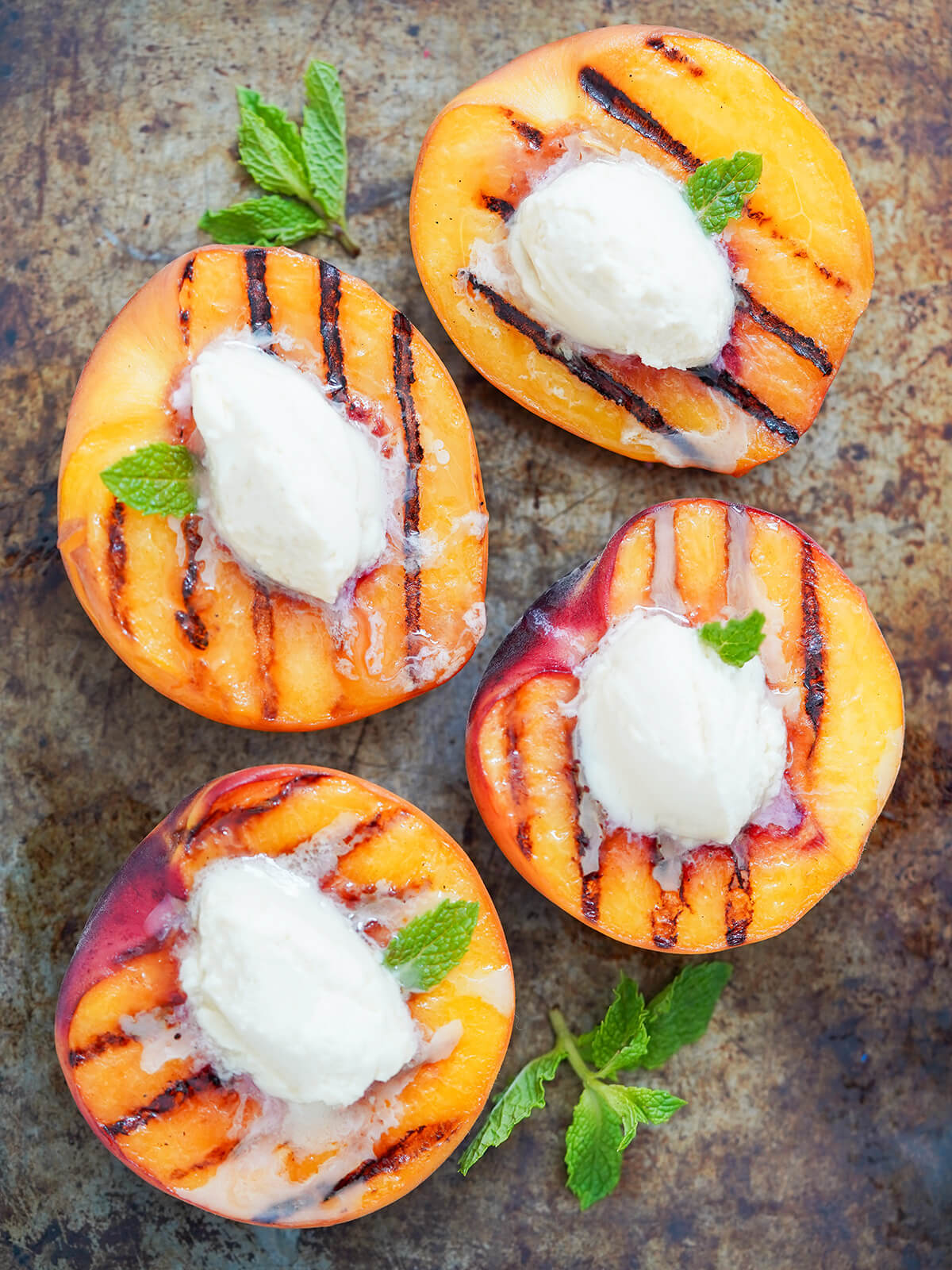 four half pieces of grilled peaches with mascarpone from overhead.