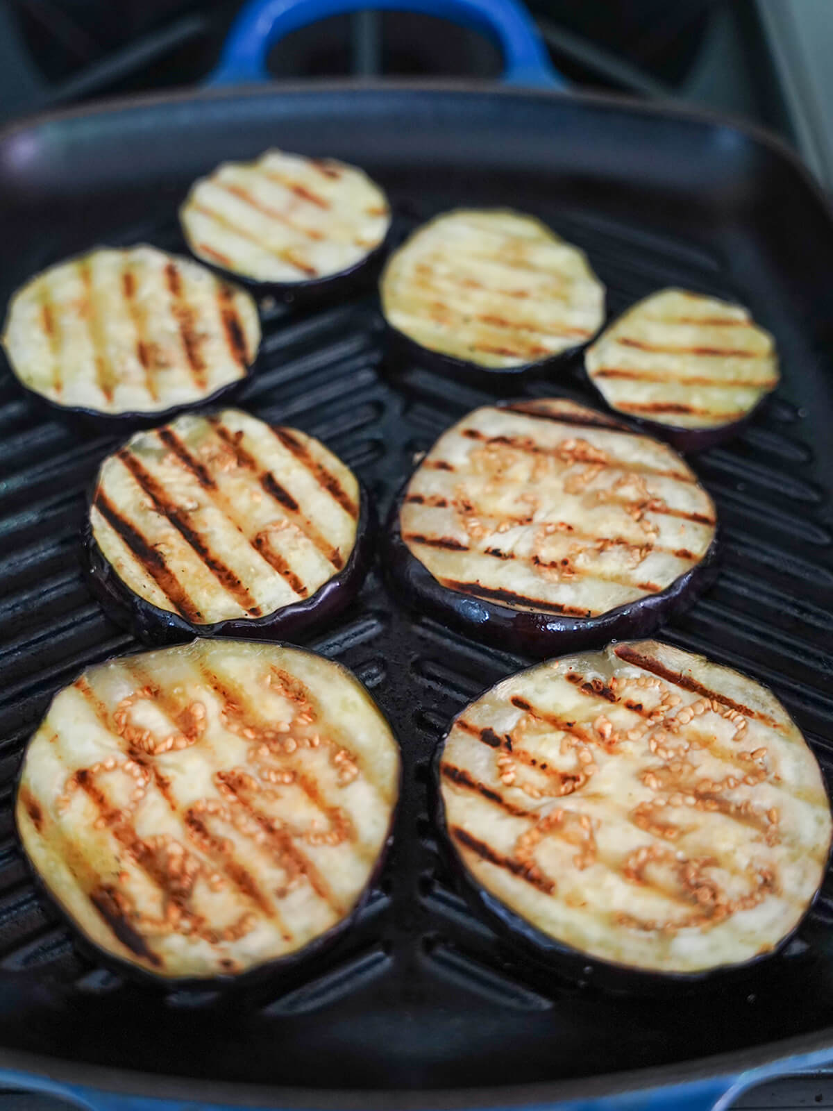 slices of eggplant on grill pan with grill marks on top side.