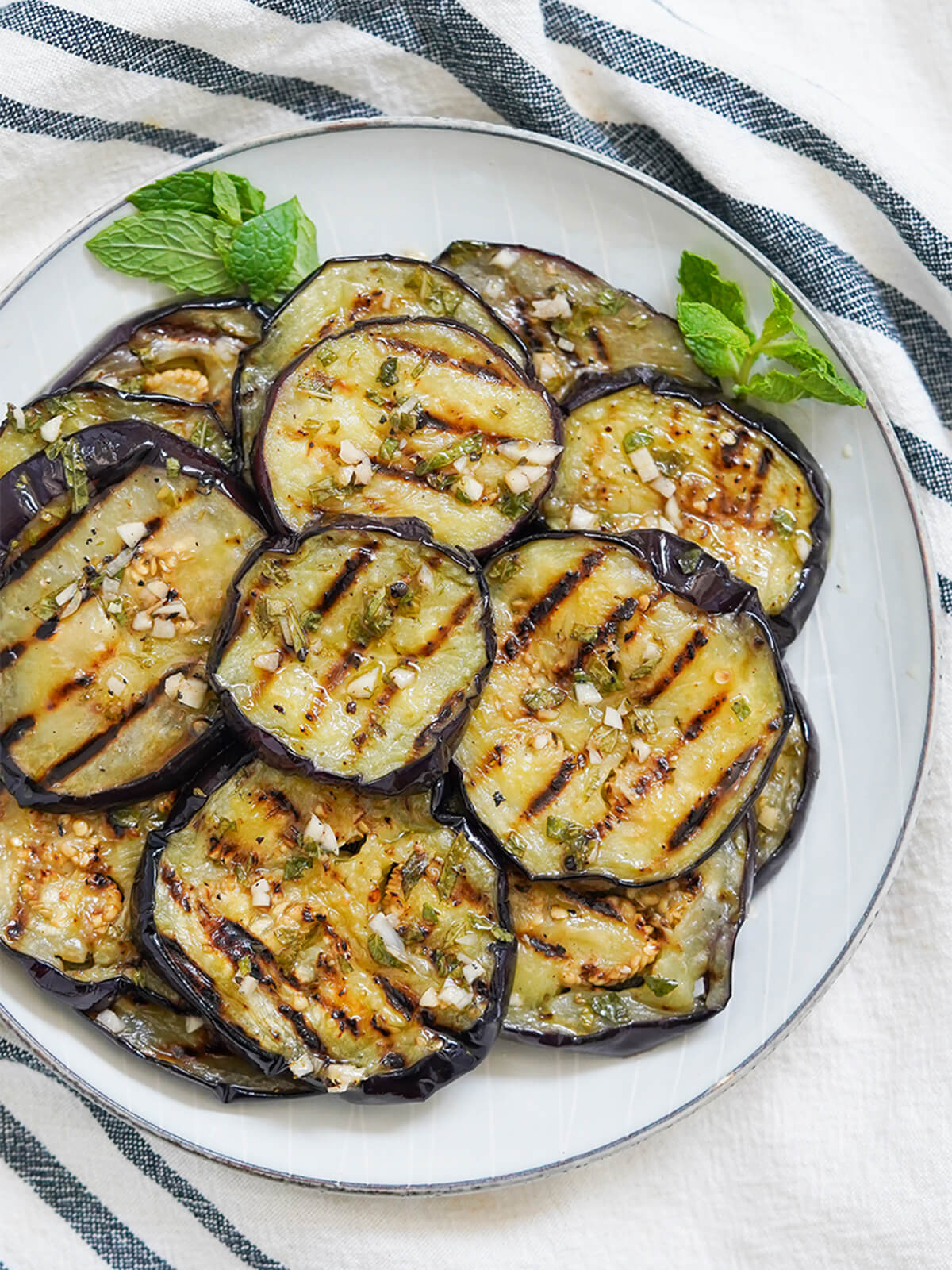 plate of marinated eggplant from overhead with mint garnishes.