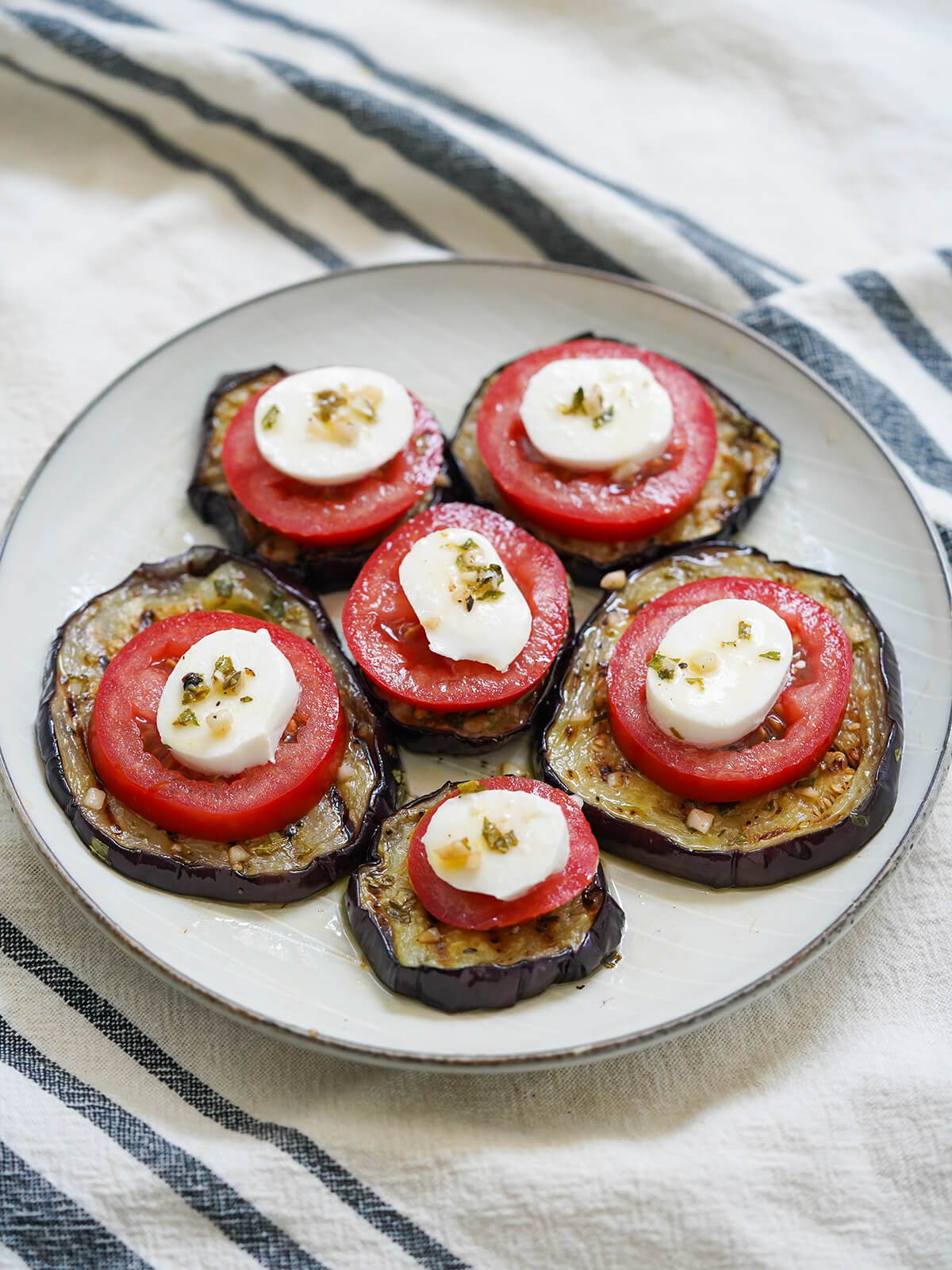 slices of marinated eggplant topped with sliced tomato and mozzarella.