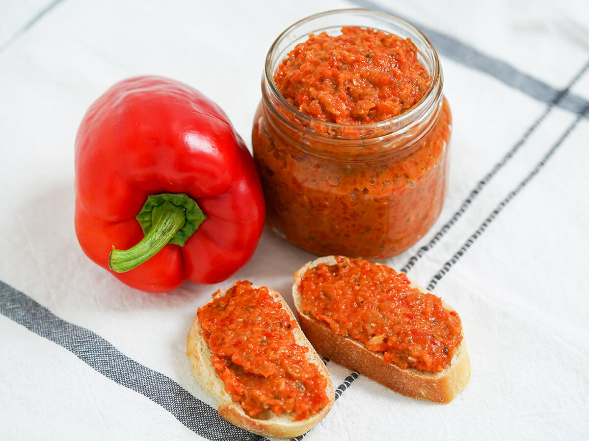 jar of ajvar red pepper spread jar of ajvar red pepper spread with pepper to side and two slices topped with the spread in front.
