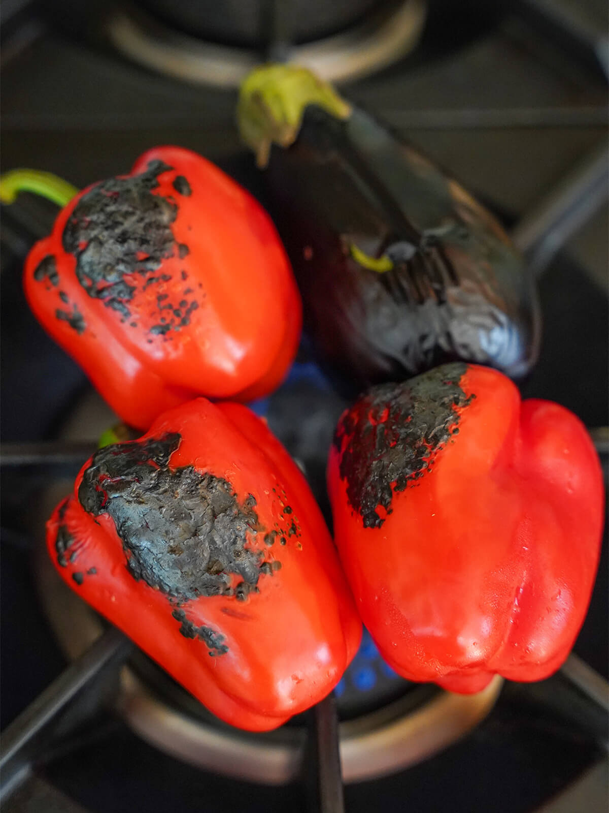 charring vegetables for ajvar red pepper spread charring peppers and eggplant over gas flame.