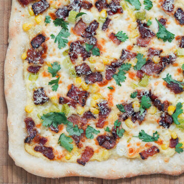 close up of corner of corn pizza with bacon.