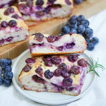 slices of Schiacciata all&rsquo;uva grape focaccia on plate with grapes behind.